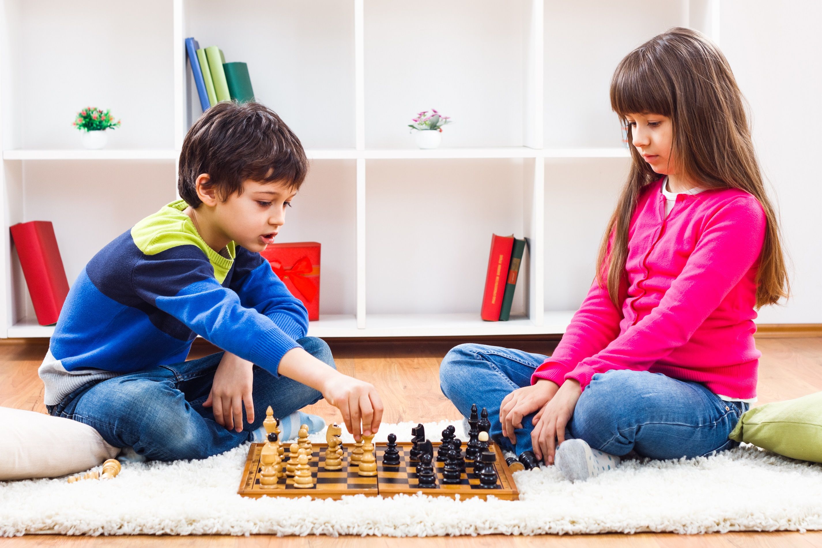 A young boy and girl playing chess together.