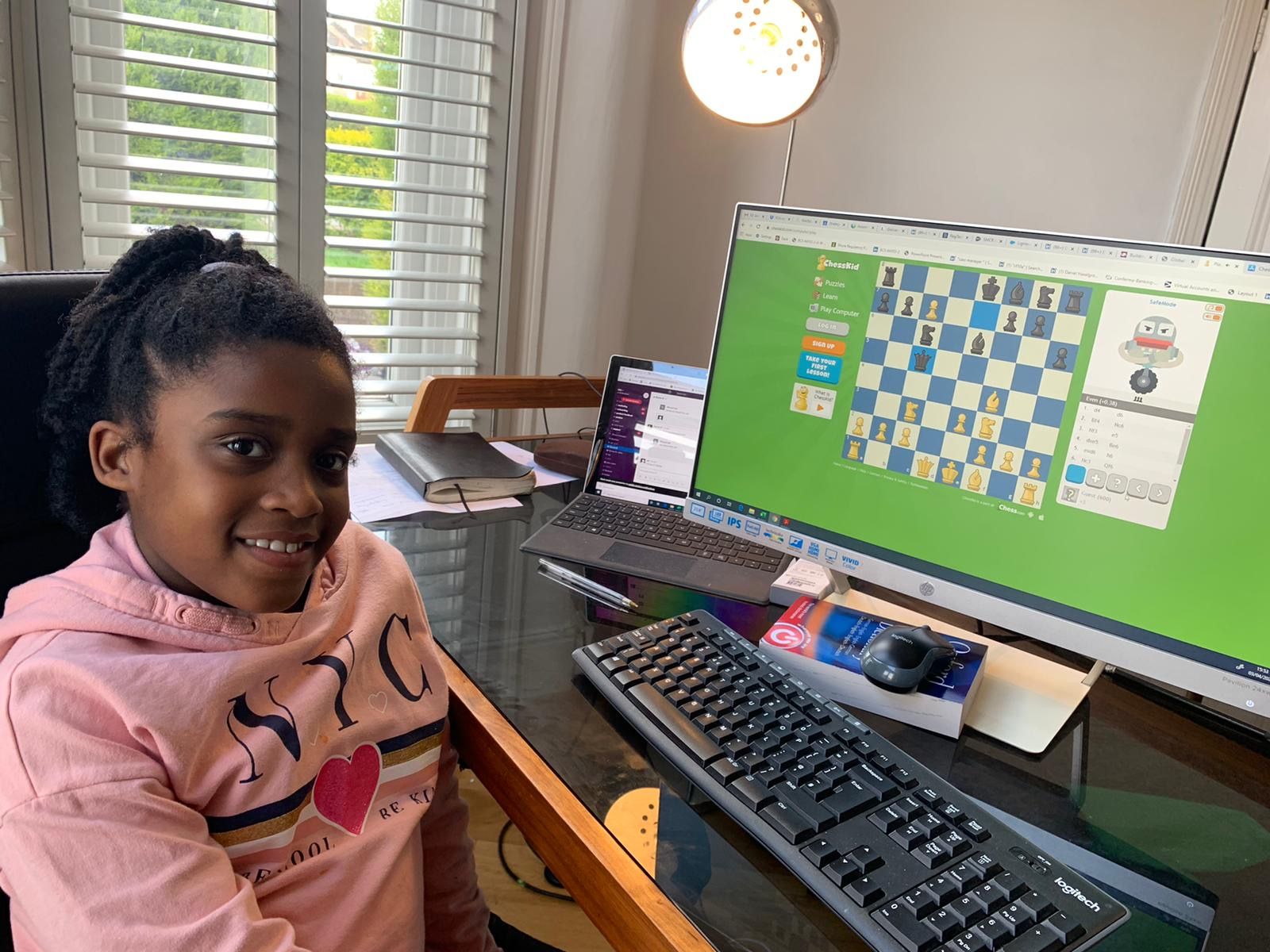 A young girl using ChessKid on her home computer.